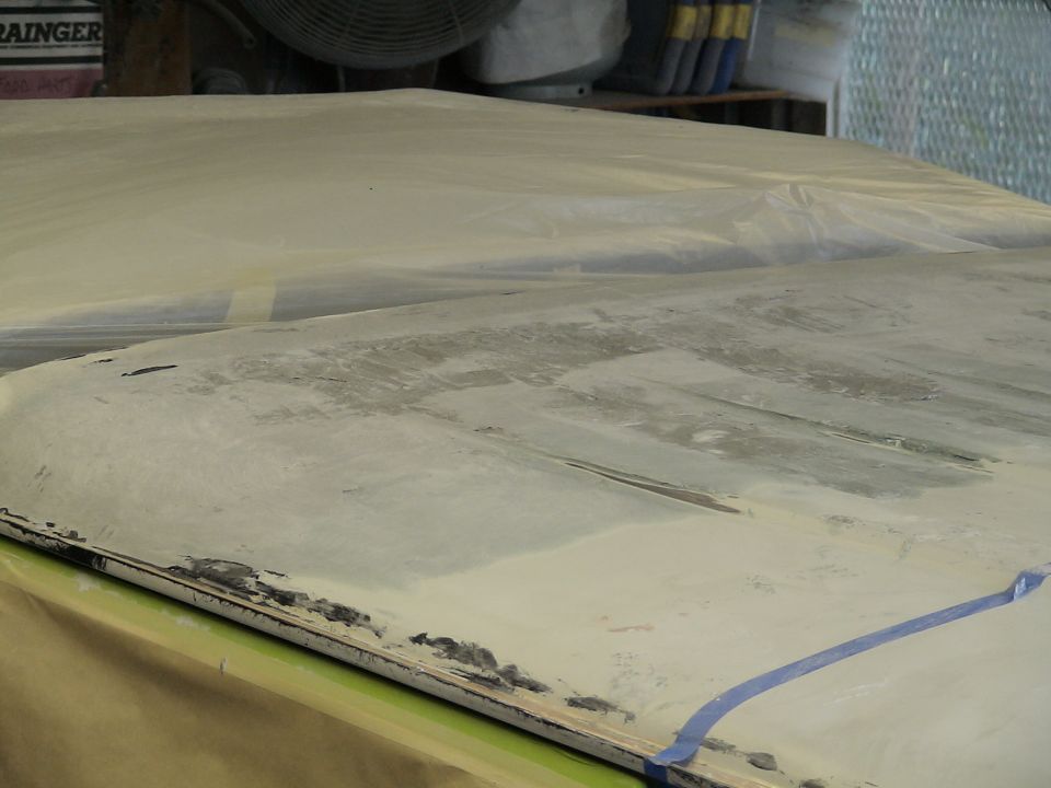 Body panel masked with paper and tape in a shop, primer and bodywork in progress