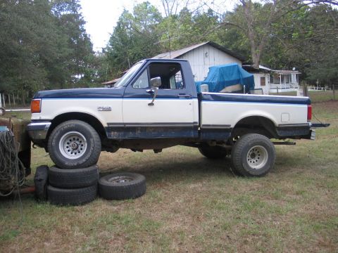 1989 Ford F-150 - Side view of a 1989 Ford F-150 pickup truck with a blue tarp covering cargo in the bed.