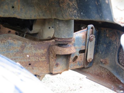 1989 Ford F-150 - Close-up view of the heavily rusted frame and shock absorber mount on a truck.