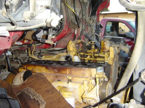 1992 Ford Bronco - View of an engine compartment, showing the engine block and various hoses and wires. A red truck is visible in the background.