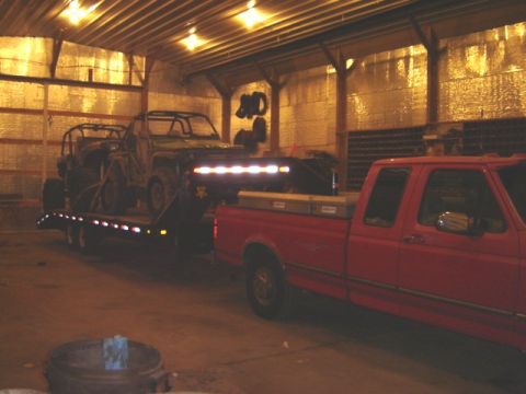 1992 Ford Bronco - Red pickup truck tows a trailer loaded with ATVs in a barn.