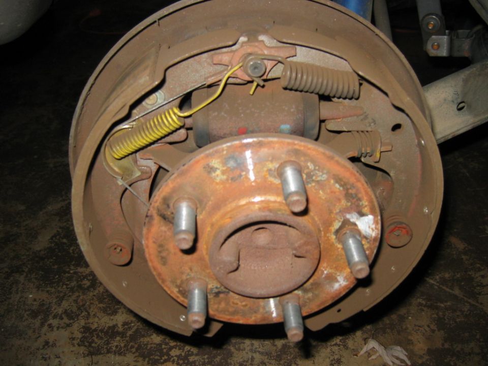Rear drum brake assembly with rusty hub and yellow springs