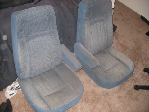 1991 Ford Bronco - A pair of front car seats with blue fabric upholstery and armrests are shown indoors.