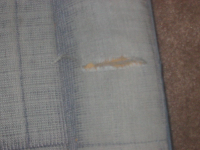 Torn light blue fabric with a horizontal rip revealing tan material underneath