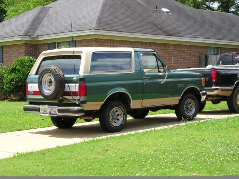 1989 Ford Bronco - This 1989 Ford Bronco is parked in front of a brick house, with a black pickup truck beside it.