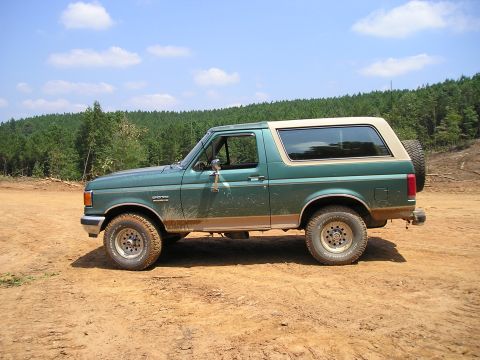 1989 Ford Bronco - Side view of a green 1989 Ford Bronco on a dirt path.