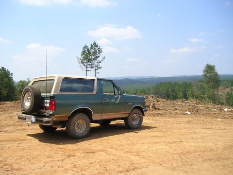 1989 Ford Bronco - This 1989 Ford Bronco is parked on a dirt lot with a scenic view of forested hills.