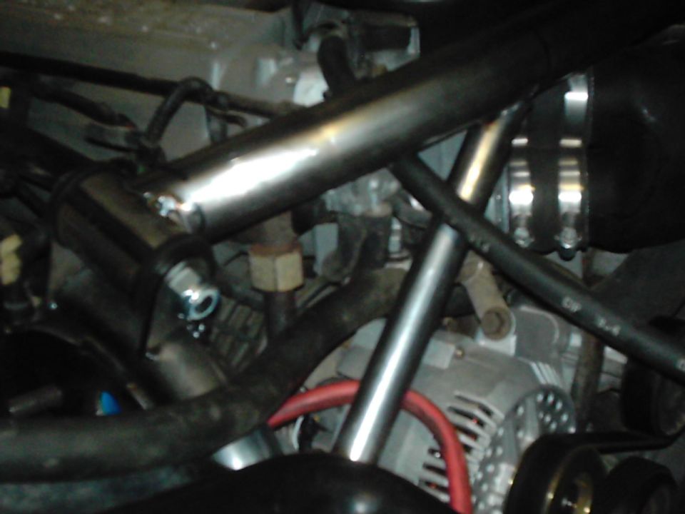 Close-up of engine bay with hoses, pipes, and alternator visible
