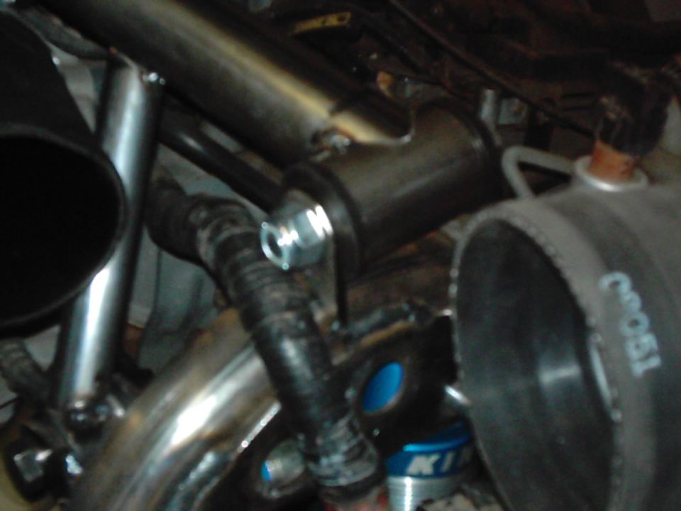 Close-up of engine hoses and metal tubing with a bolt and clamp
