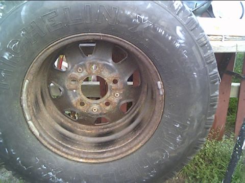 1981 Ford Bronco - A close-up view of a tire and rim, with visible text on the tire and rust on the rim.