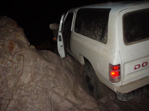 1981 Ford F-150 - A white Dodge Ramcharger is stuck on a rocky incline, with its driver's door open.
