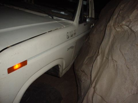 1981 Ford F-150 - A white pickup truck is partially obscured by a large object on its right side.