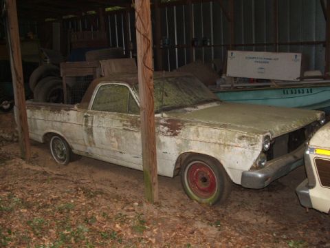 1966 Ford Ranchero - A weathered 1965 Ford Ranchero sits in a shed, partially obscured by wooden posts and other stored items.