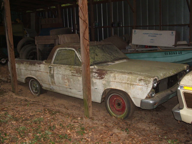 White 1965 Ford Ranchero, weathered, parked in a shed next to another vehicle