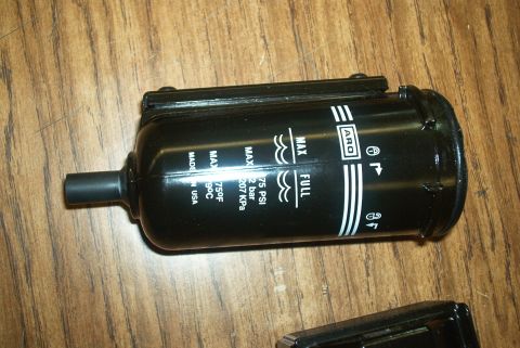 1983 Ford Bronco - A black ARO fluid filter with measurement markings for MAX and FULL levels is shown on a wooden surface.