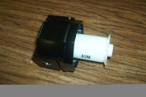1983 Ford Bronco - Automotive part with white cylindrical component and black housing shown on a wooden surface.