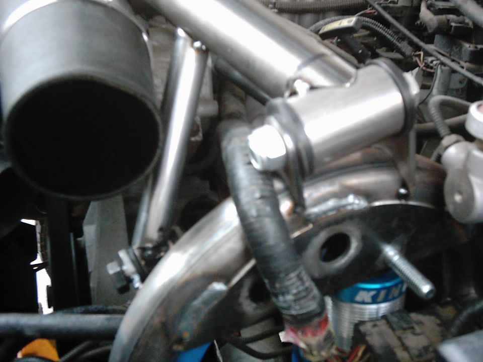 Close-up of custom exhaust piping and engine components, with a blue 'KING' shock absorber visible