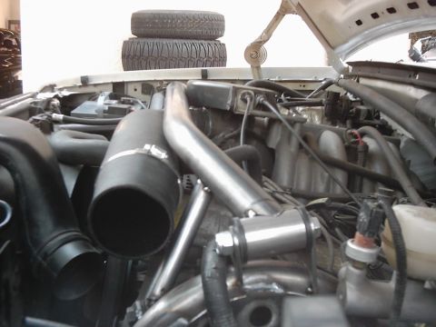 1978 Ford Bronco - Custom intake system visible in the engine bay, with two tires stacked above.