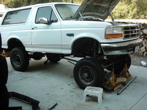 1978 Ford Bronco - This white Ford Bronco is shown with its hood up and the front end elevated on jack stands for maintenance.