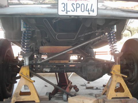 1978 Ford Bronco - The underside of a vehicle is shown with its rear axle and suspension components elevated on jack stands.