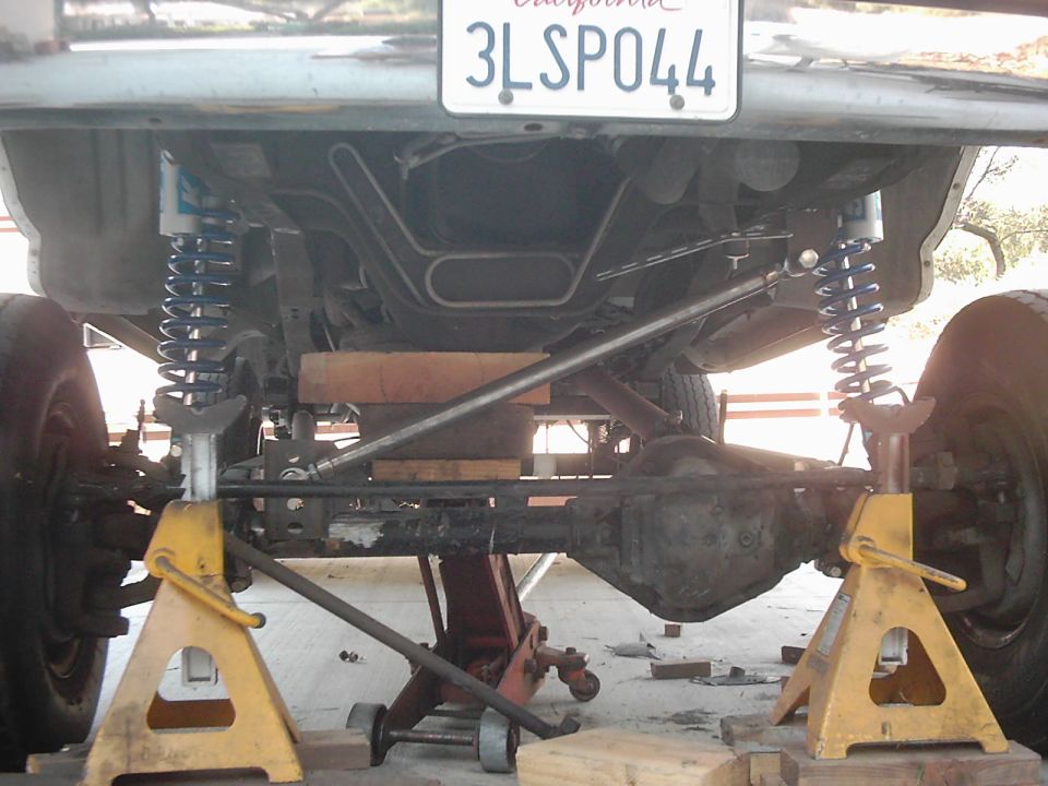 Rear axle and suspension of a vehicle on jack stands. California license plate 3LSP044 is visible