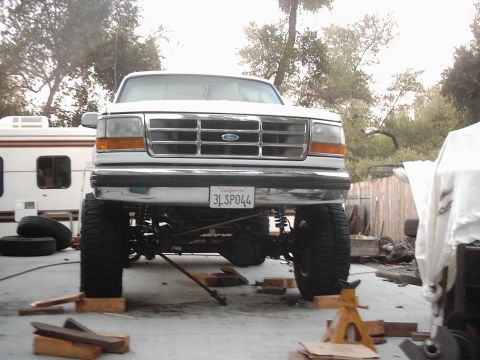 1978 Ford Bronco - White Ford F-series truck with lifted suspension, parked in a driveway with an RV in the background.