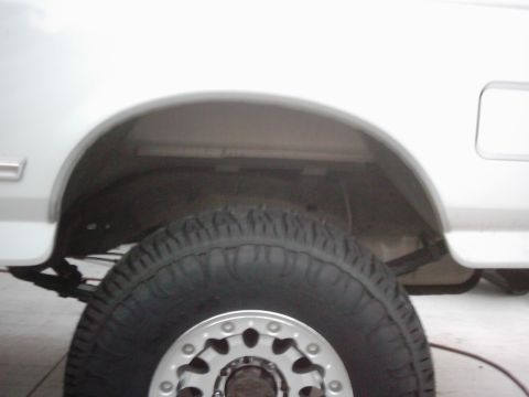 1978 Ford Bronco - The rear wheel well and tire are visible on the side of a white vehicle.