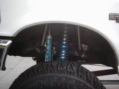 1978 Ford Bronco - Close-up of the suspension system within the wheel well of a white vehicle.