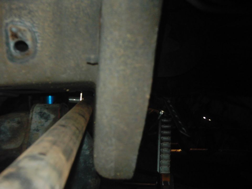 Close-up of vehicle undercarriage with a rusty pipe and some blue component visible