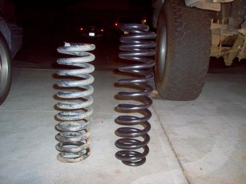 1988 Ford Bronco - Comparison of old and new coil springs, with a vehicle tire visible in the background.