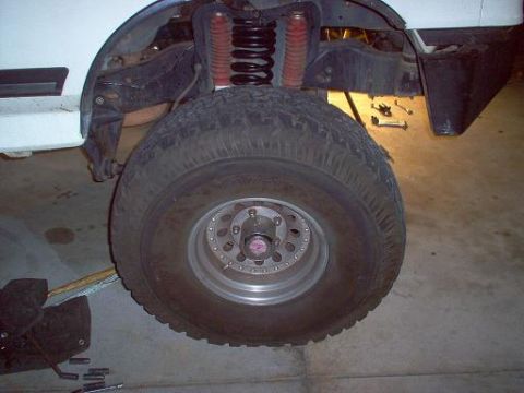 1988 Ford Bronco - Front suspension and tire of a 1988 Ford Bronco, likely undergoing maintenance or modification.