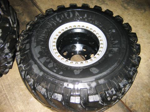 1985 Ford Bronco - A close-up view of a large off-road tire mounted on a black wheel with a chrome ring.