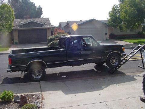 1971 Ford Bronco - A black Ford F-Series pickup truck is positioned on a ramp in a suburban driveway.