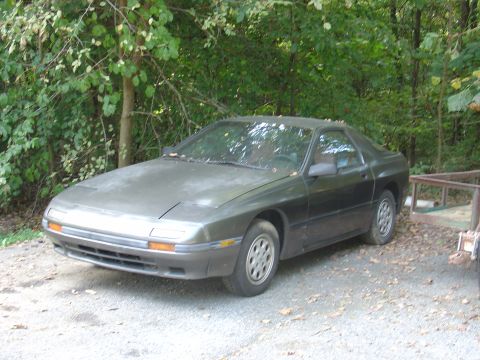 1986 Mazda RX-7 - This 1986 Mazda RX-7 is parked in a wooded area.