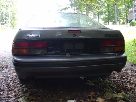 1986 Mazda RX-7 - Rear view of a dark gray 1986 Mazda RX-7 parked outdoors, showing its taillights and bumper.