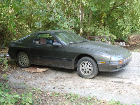 1986 Mazda RX-7 - This 1986 Mazda RX-7 is parked in an outdoor setting with foliage surrounding it.