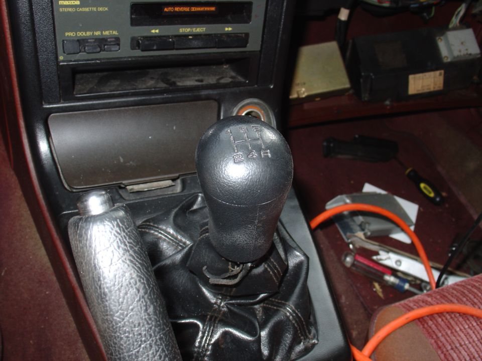 5-speed shift knob and boot in Mazda interior with cassette stereo and tools on floor