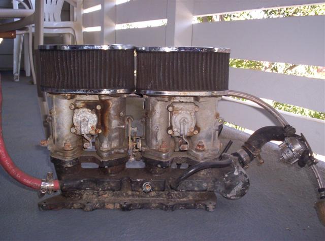 Dual carburetors with chrome-ringed air filters and a red hose attached