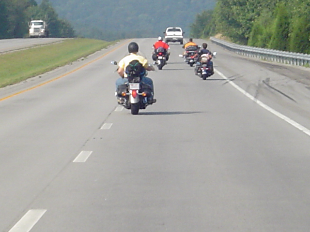 Group of motorcycles riding on a highway with cars in the distance