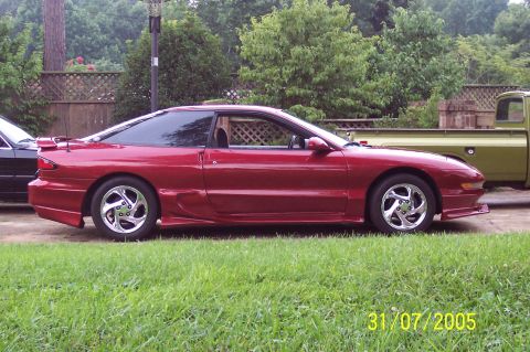 1995 Ford Probe - A red 1995 Ford Probe coupe is parked next to a green pickup truck.