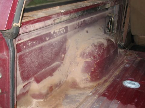 1991 Ford Bronco - The dusty interior cargo area of a vehicle, with visible wiring and metal panels.