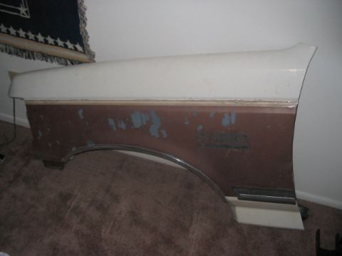 1991 Ford Bronco - A detached vehicle fender shows signs of wear and tear, with rust and chipped paint visible.
