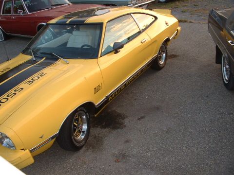 1978 Ford Mustang II - A yellow 1978 Ford Mustang II Mach 1 is parked next to other vehicles.