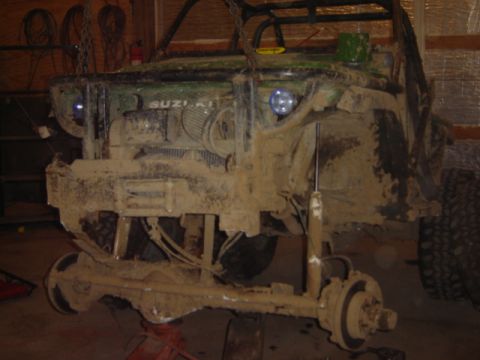1992 Ford Bronco - This heavily soiled Suzuki Samurai is undergoing repairs in a workshop, with its front axle removed.