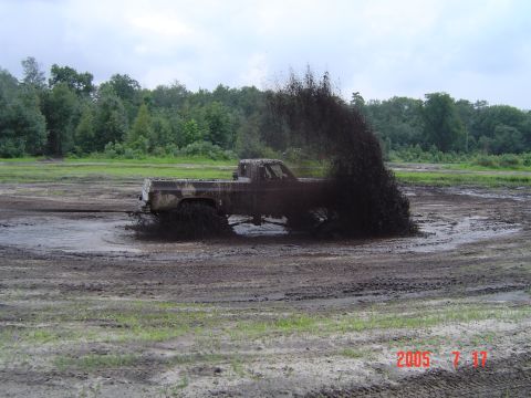 2005 Dodge 1500 - A truck navigates a muddy terrain, sending a large plume of mud into the air.