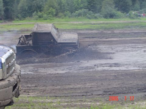 2005 Dodge 1500 - A truck navigates a muddy track, kicking up a large spray of water and mud.