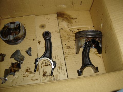 1988 Ford Bronco - Engine parts, including damaged pistons and connecting rods, are laid out in a box.