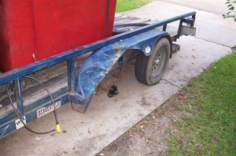1987 Ford Bronco - A trailer is parked on a concrete surface, showing a missing wheel and exposed hub assembly.