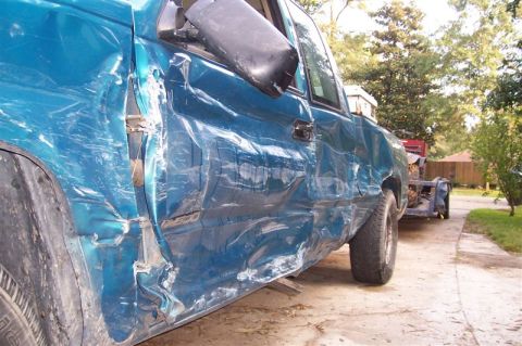 1987 Ford Bronco - This blue pickup truck sustained significant damage to its driver's side, impacting the door and fender.