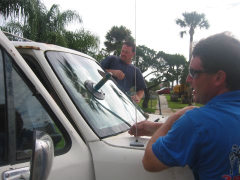 1989 Ford Bronco - Two men are working on replacing the windshield of a white truck.